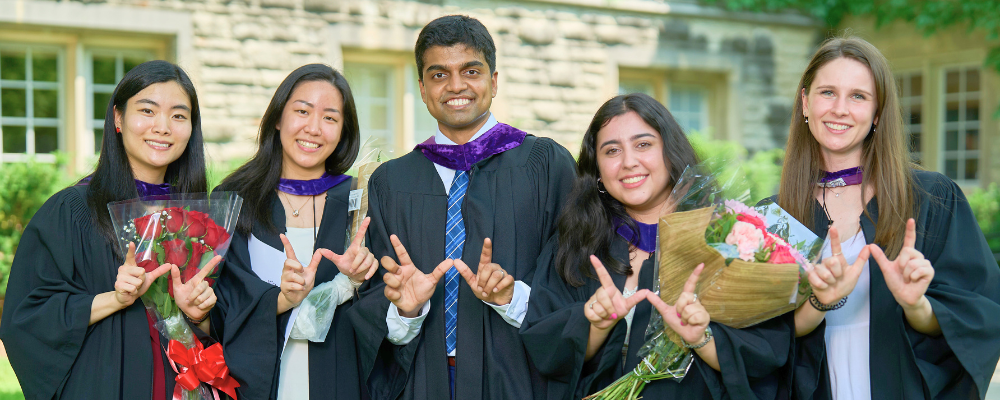 A group of Western Law students in their academic robes stand side by side with their hands making the Western W sign