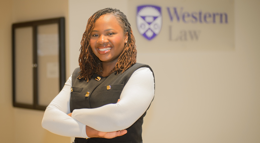 A photo of Moyosore Somide with her hands crossed in front of a Western Law sign.